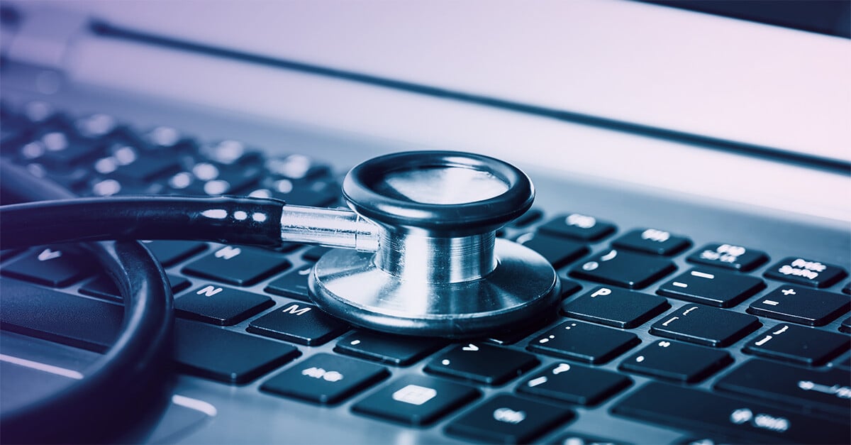 A stethoscope rests on a laptop keyboard.