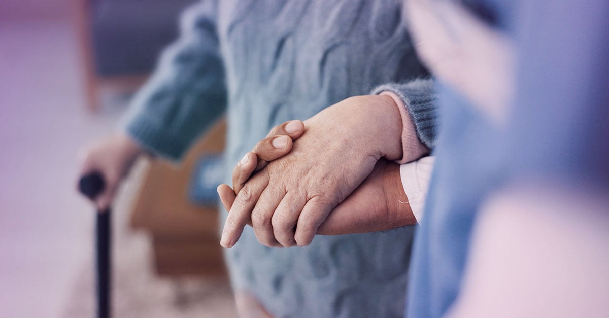 elderly person holds the hand of a caregiver